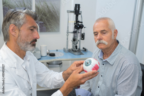 ophthalmologist with eye model showing senior patient