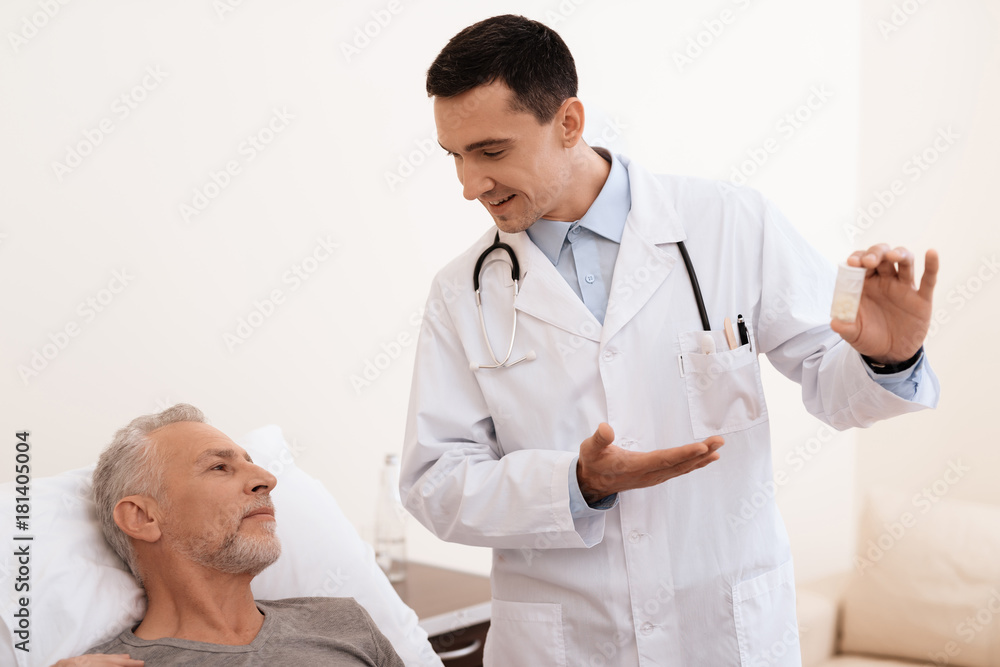 The old man lies on a cot in the medical ward, and next to him stands a doctor. He explains something to the old man. The old man lies on a cot in the medical ward, and next to him stands a doctor. He explains something to the old man.