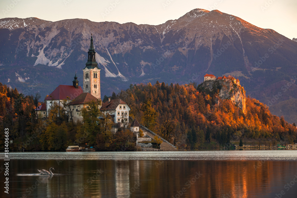 Fototapeta premium Bled, Slovenia - Beautiful autumn sunrise at Lake Bled with the famous Pilgrimage Church of the Assumption of Maria with Bled Castle and Julian Alps at background