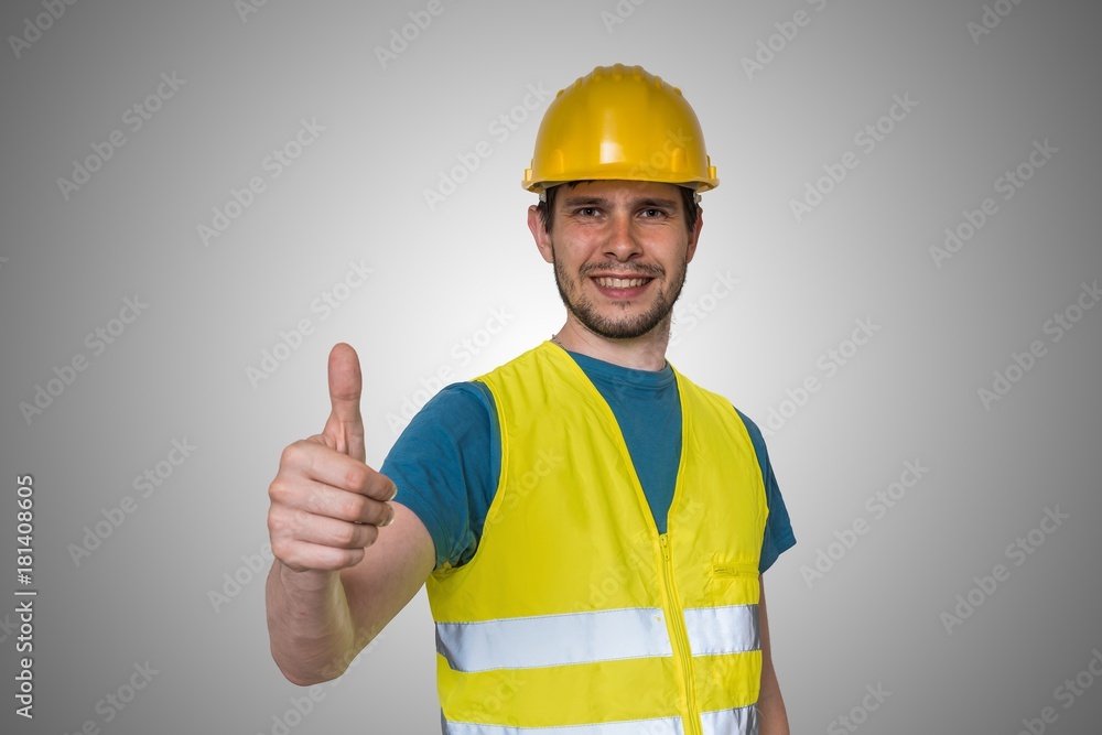 Young happy construction worker in yellow helmet is showing thumbs up gesture. Young happy construction worker in yellow helmet is showing thumbs up gesture.