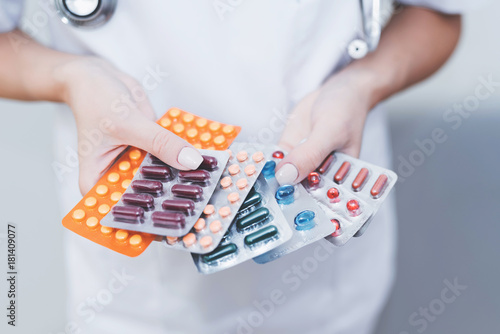 Close up. A nurse is holding various pills in her hands. She is eating them in her hands.