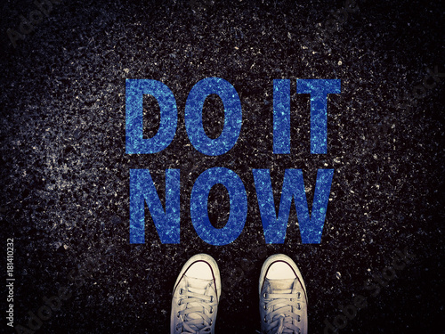 Do it now word and sneakers shoes on grunge road