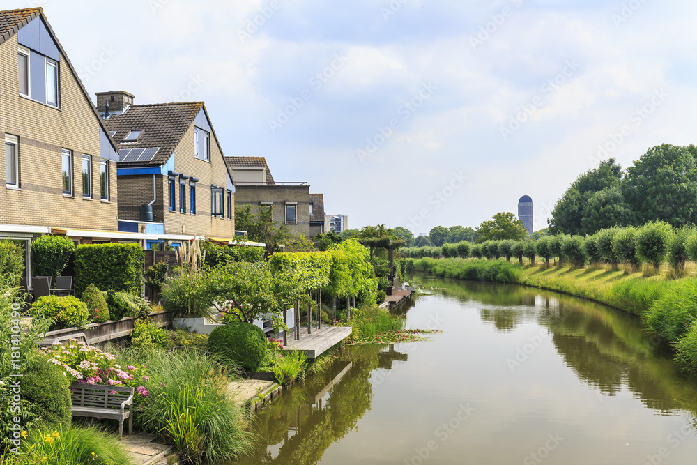 Residential houses on the waterside with a water tower on the background located in Rokkeveen, Zoetermeer.