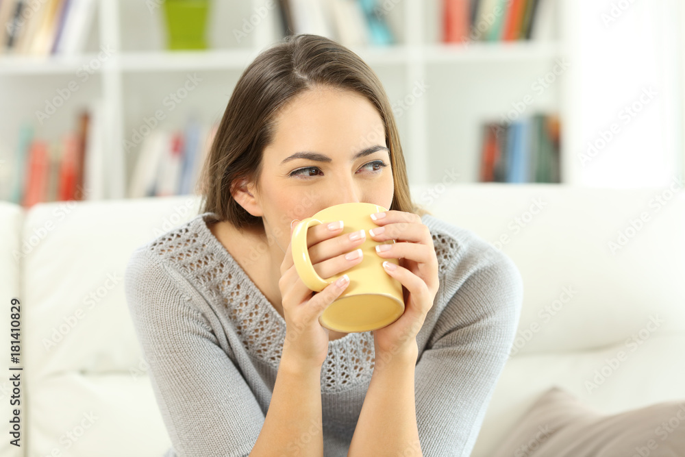 Woman drinking coffee looking at side at home Woman drinking coffee looking at side at home