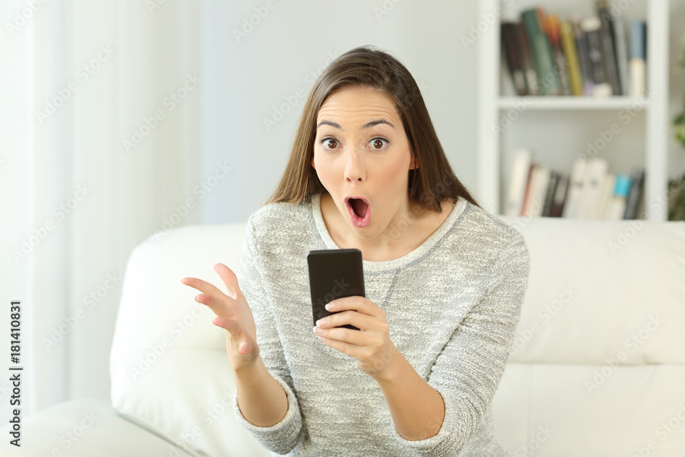 Surprised woman holding a phone looking at you Surprised woman holding a phone looking at you