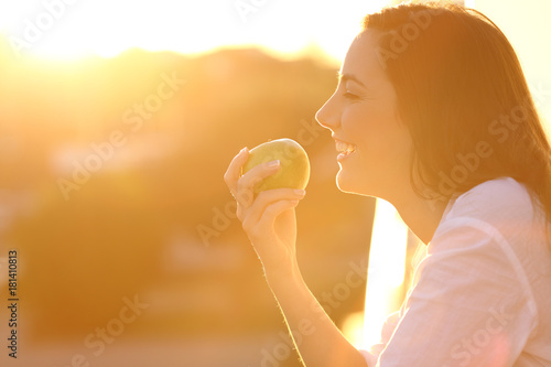 Profile of a woman eating an apple at sunset