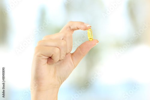 Woman hand holding a yellow vitamin pill