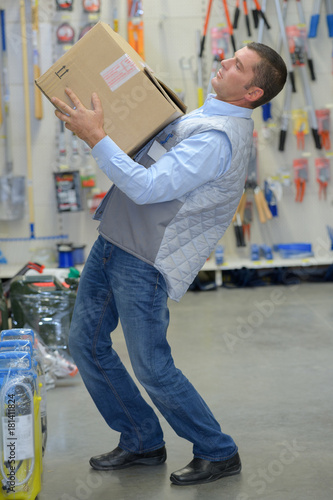 man carrying heavy cardboard box in warehouse