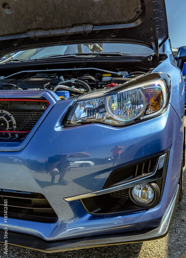 Engine component on show in a blue car with the hood popped