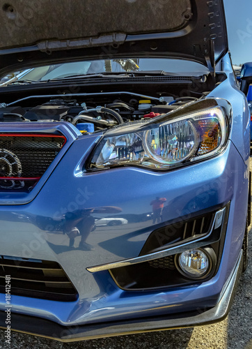 Engine component on show in a blue car with the hood popped
