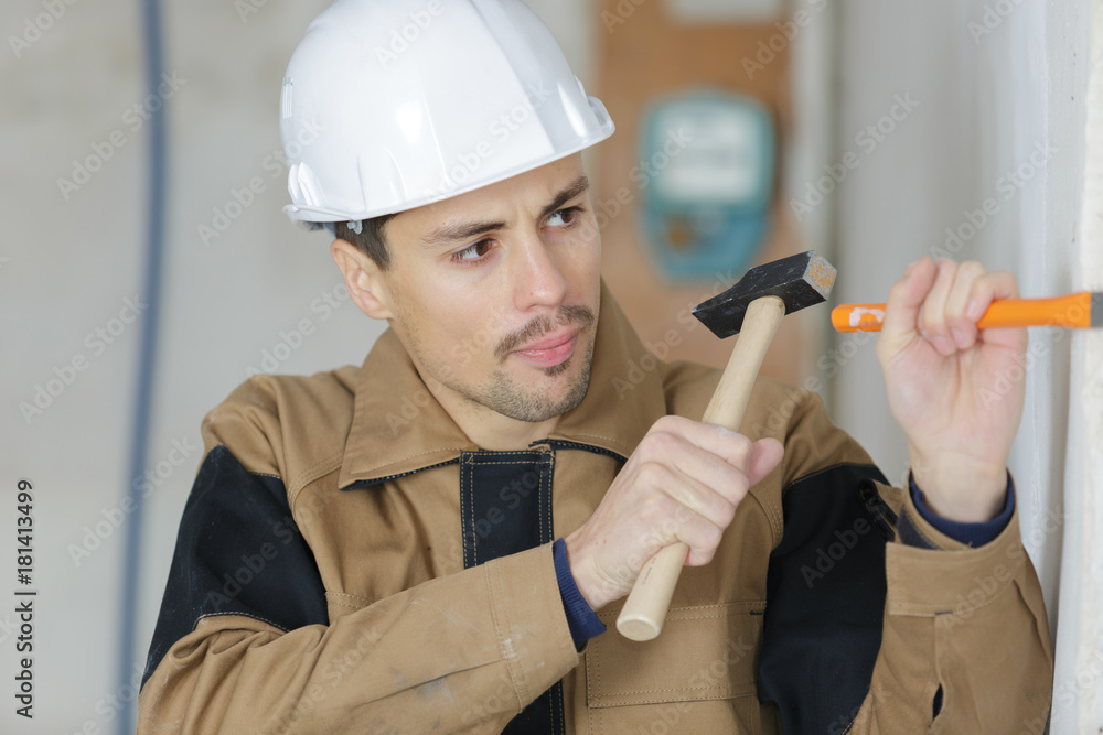 young builder using hammer to remove plaster from wall young builder using hammer to remove plaster from wall
