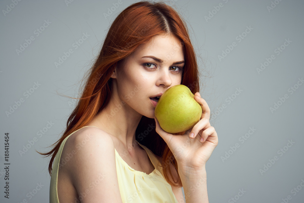 Young beautiful woman on a gray background holds an apple, diet Young beautiful woman on a gray background holds an apple, diet