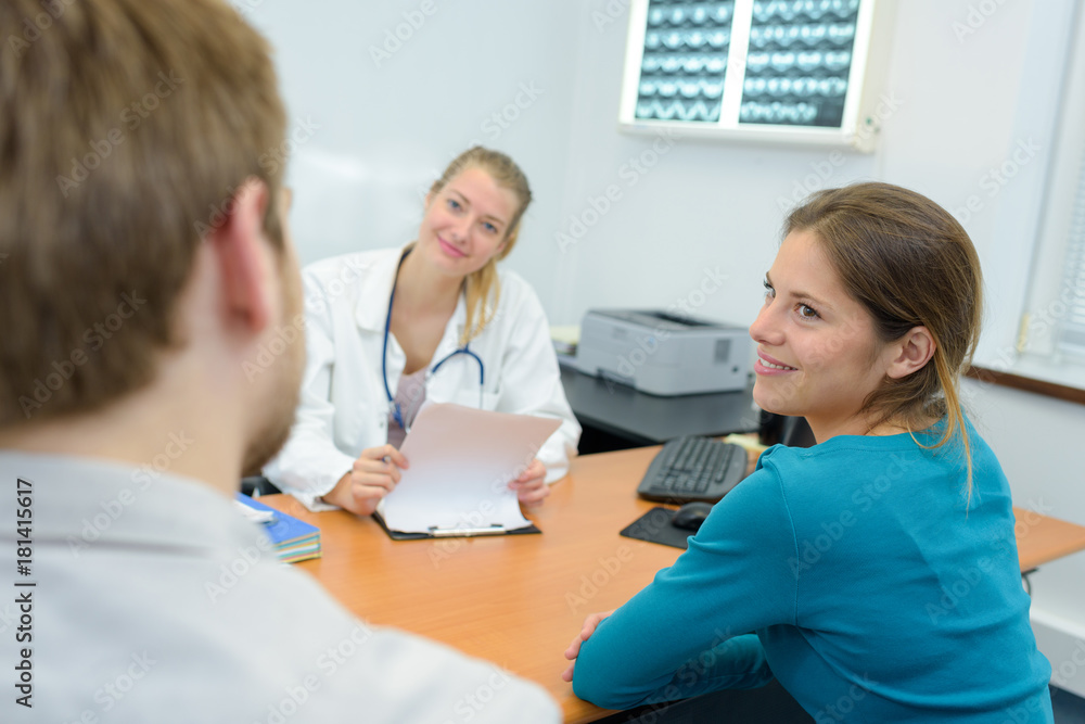 Obraz premium happy young couple giving envelope to female doctor