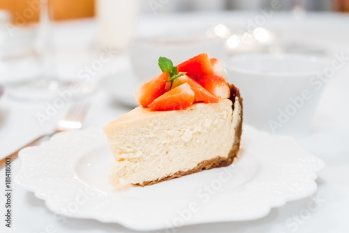 Cheesecake with strawberries and mint leaves on a white plate