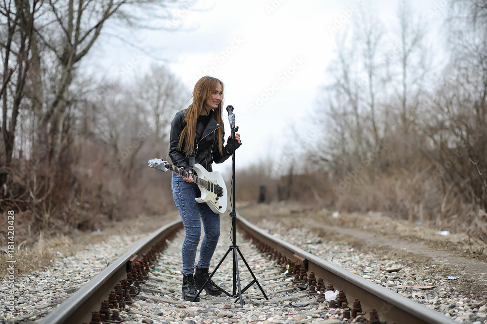  A rock musician girl in a leather jacket with a guitar 