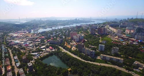 Wallpaper Mural Flying backwards above Vladivostok residential district with streets, houses, Mine Park (Minny Gorodok) with lakes. Aerial view of the Golden horn harbour on the background. Summer day. Russia Torontodigital.ca