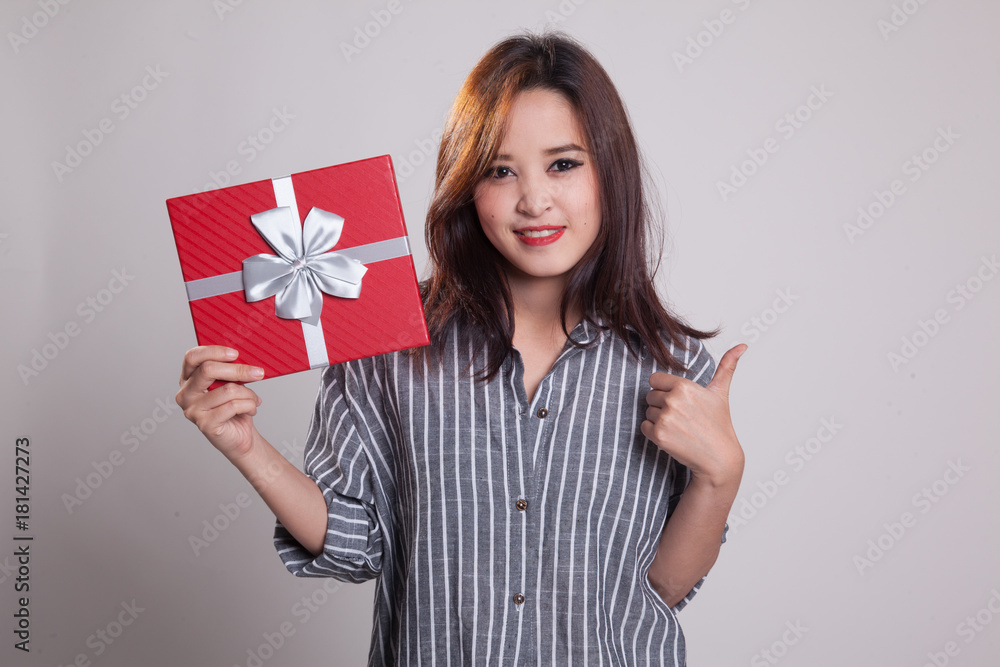 Young Asian woman thumbs up with a gift box. Young Asian woman thumbs up with a gift box.