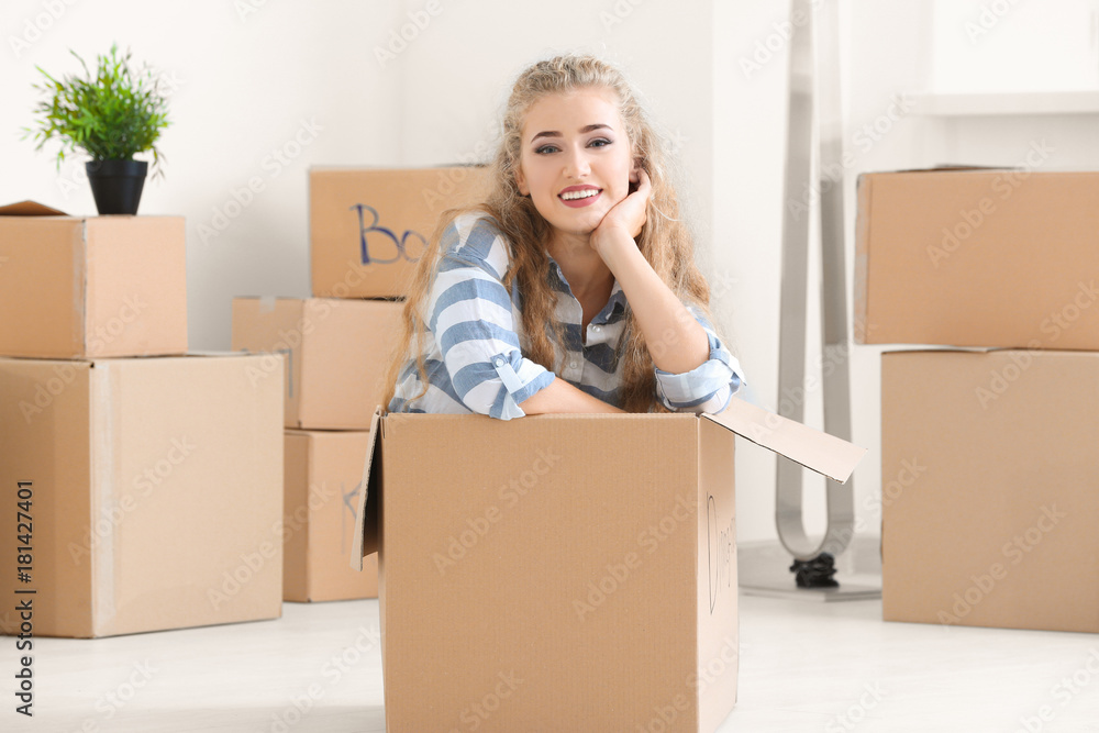 Young woman in moving box at new home Young woman in moving box at new home