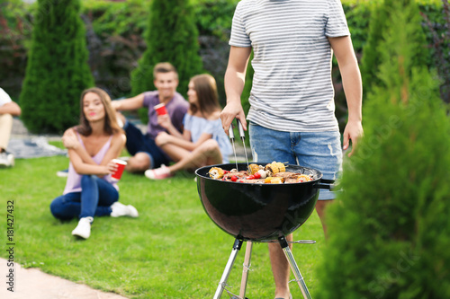 Man cooking tasty steaks on barbecue grill for party, outdoors