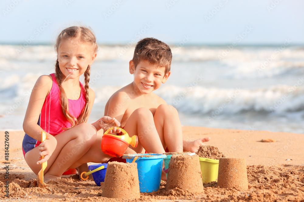 Naklejka premium Cute children playing with sand on sea beach