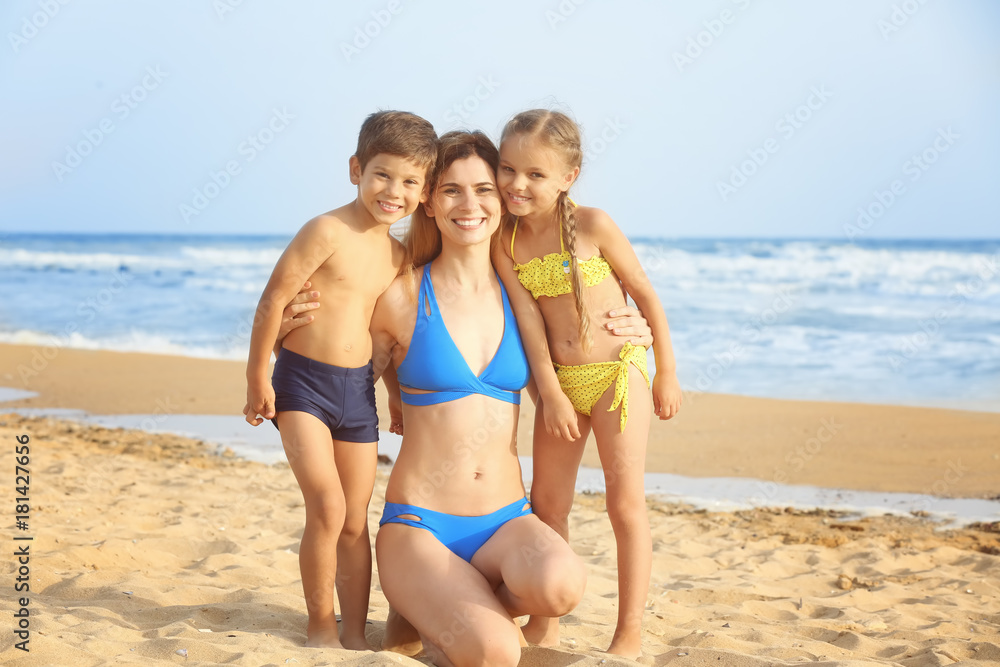 Cute little children with mother on sea beach at resort