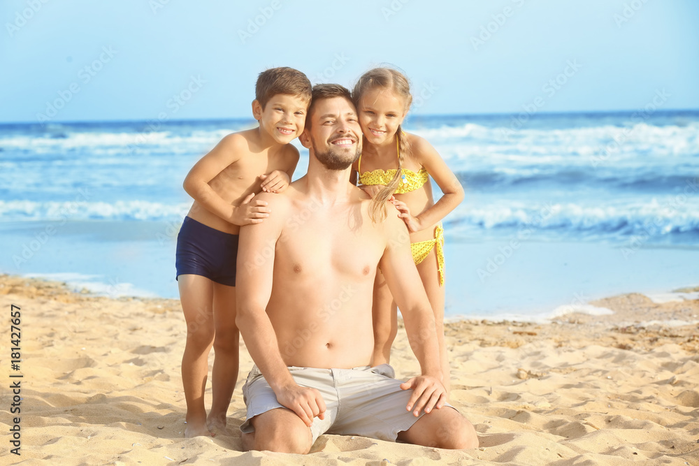 Cute little children with father on sea beach at resort