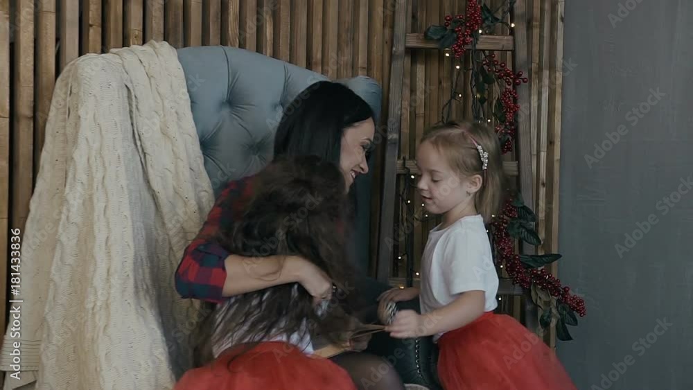 Happy little kids - brunette and blonde and their charming mother have fun on Christmas Eve. A happy family Happy little kids - brunette and blonde and their charming mother have fun on Christmas Eve. A happy family