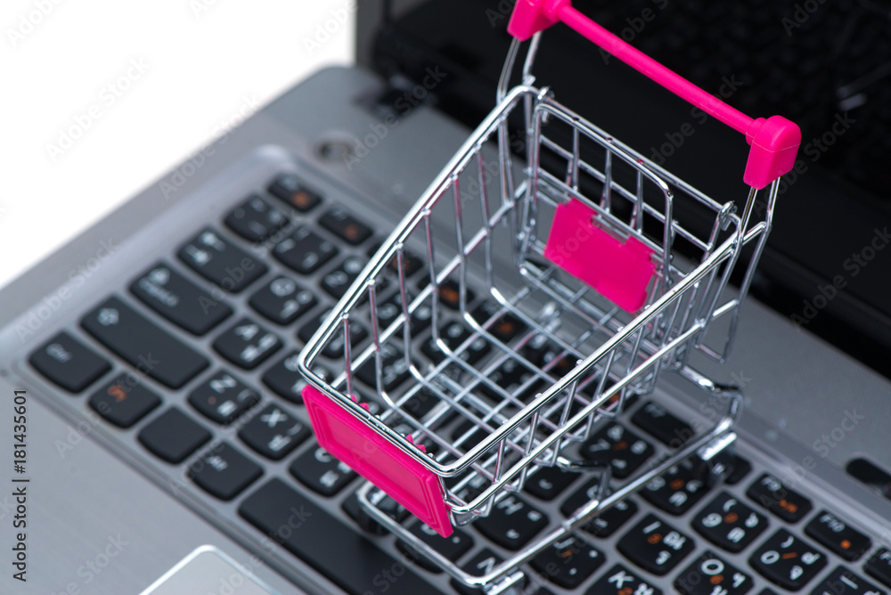 Shopping cart or supermarket trolley with laptop notebook isolated on white background, e-commerce and online shopping concept.