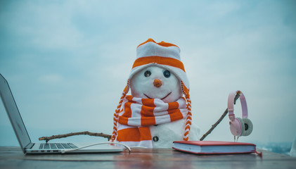 Snowman in winter with laptop, headset and book