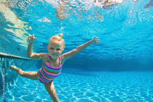 Funny portrait of child learn swimming  diving in blue pool with fun - jumping deep down underwater with splashes. Healthy family lifestyle  kids water sports activity  swimming lesson with parents.