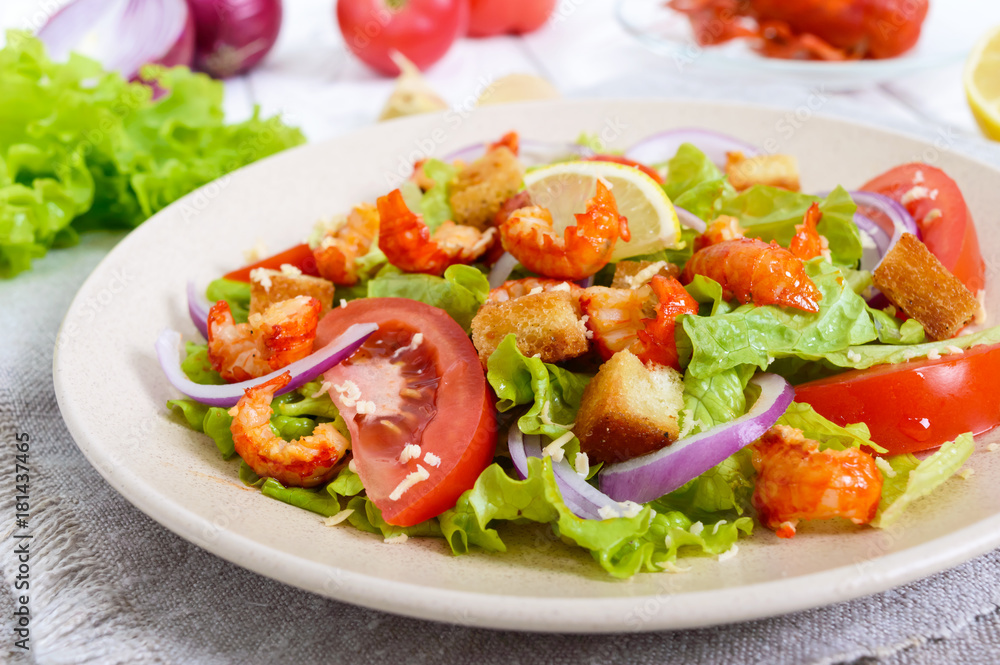 Light tasty salad with meat of a cancer, shrimps, lettuce, garlic croutons, tomatoes, red onions on a white background.