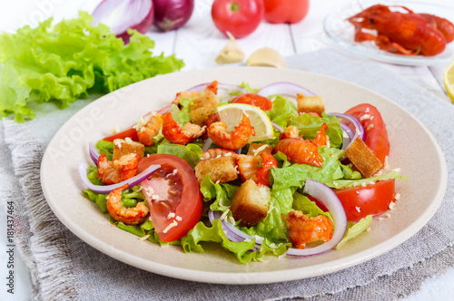 Light tasty salad with meat of a cancer, shrimps, lettuce, garlic croutons, tomatoes, red onions on a white background.
