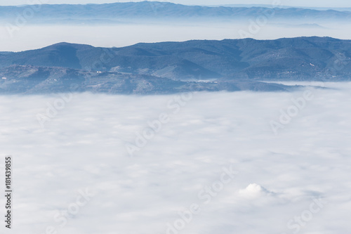 Fog filling a valley between some mountains and hills © Massimo