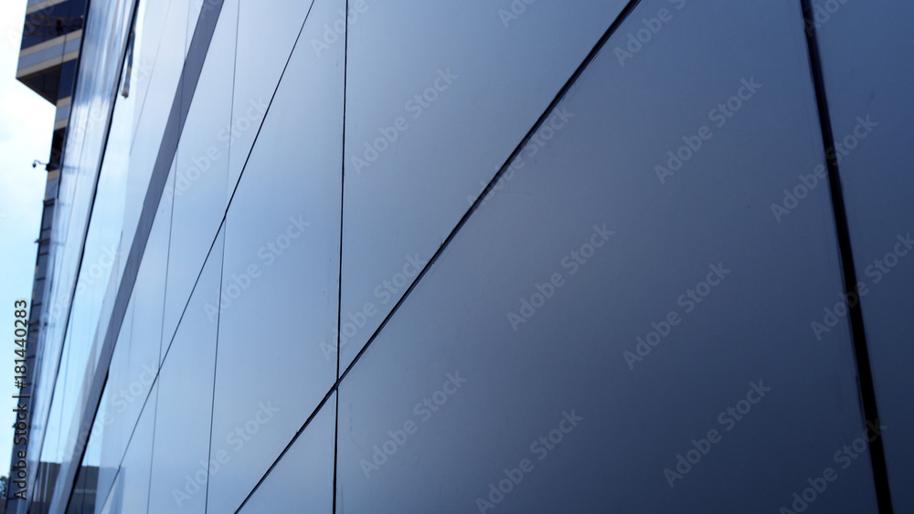 Perspective wide large grey square tile wall board of modern building, with blurred glass window background, in sunset evening light shade and shadow Perspective wide large grey square tile wall board of modern building, with blurred glass window background, in sunset evening light shade and shadow
