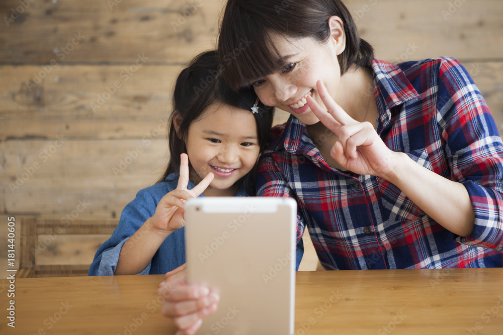 Mother and daughter are using a digital tablet at the table together. Mother and daughter are using a digital tablet at the table together.