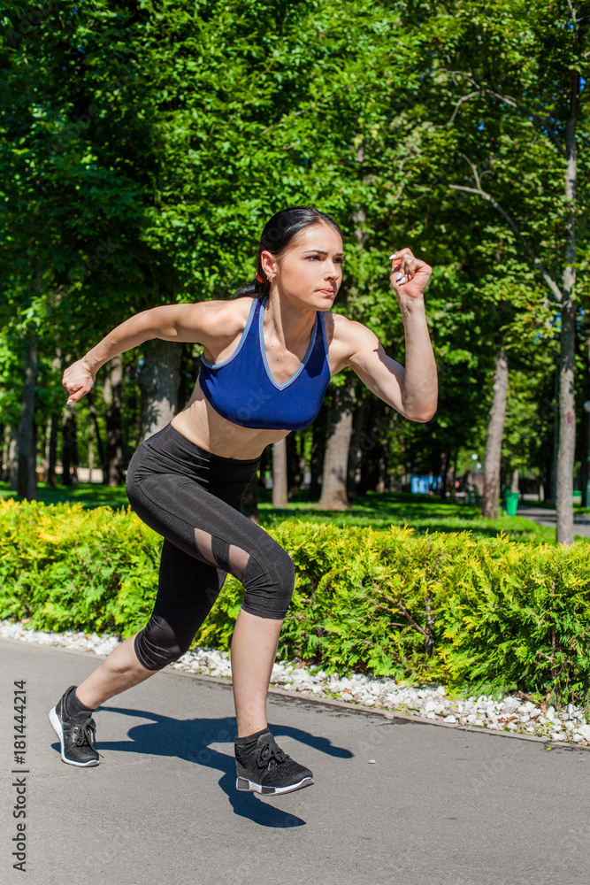 Young sportive teenager in a bright blue sport bra and black leggings  running in the nature. Photo of an athlete girl with a beautiful sports  body Stock Photo