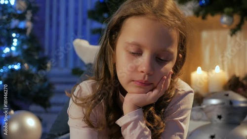 Dolly shot of cute girl writing letter to santa at living room with fireplace photo