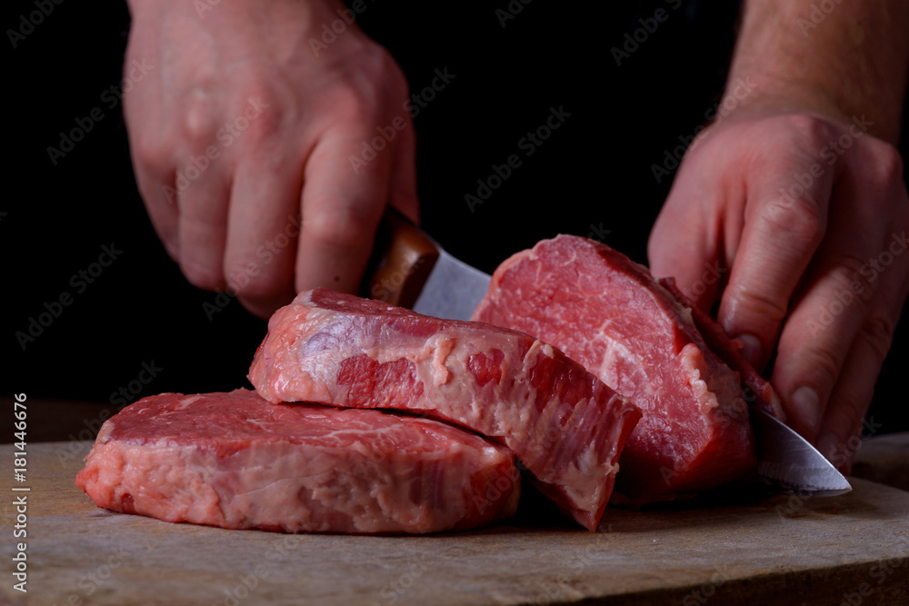 Man cuts beef meat on cutting board