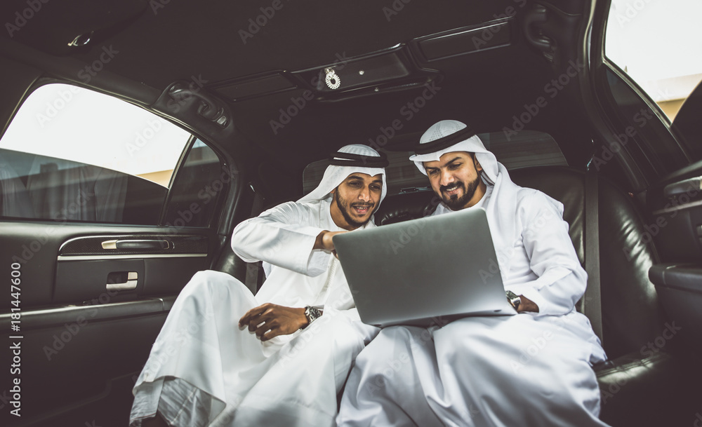 Obraz premium Dwóch arabskich biznesmenów rozmawia o biznesie w firmowej limuzynie