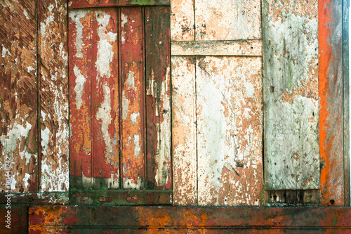 Old grunge and weathered red, white and green wooden wall planks texture background marked by long exposure to the elements outdoors.