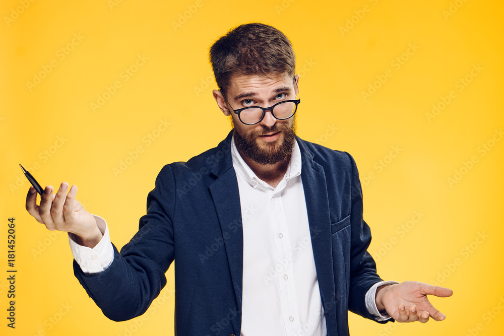 Businessman in glasses holds a pen, a man with a beard on a yellow background, emotions Businessman in glasses holds a pen, a man with a beard on a yellow background, emotions