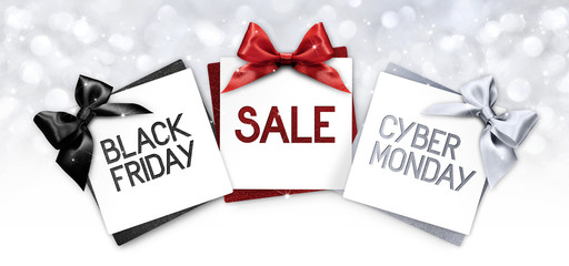 black friday and cyberg monday sale text write on gift card label with black, red and silver ribbon bow on blurred bright lights background