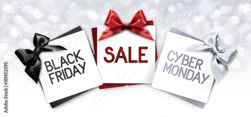 black friday and cyberg monday sale text write on gift card label with black, red and silver ribbon bow on blurred bright lights background