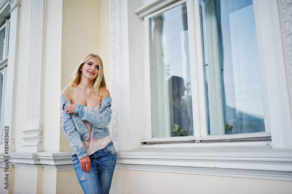 Blonde girl wear on jeans posed against old house. Blonde girl wear on jeans posed against old house.