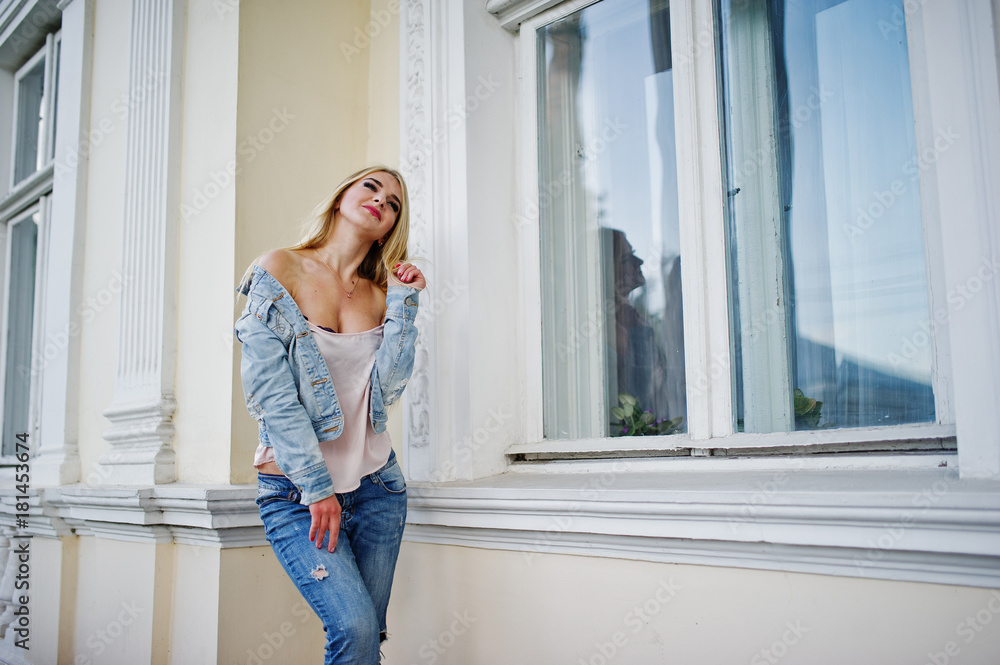 Blonde girl wear on jeans posed against old house. Blonde girl wear on jeans posed against old house.