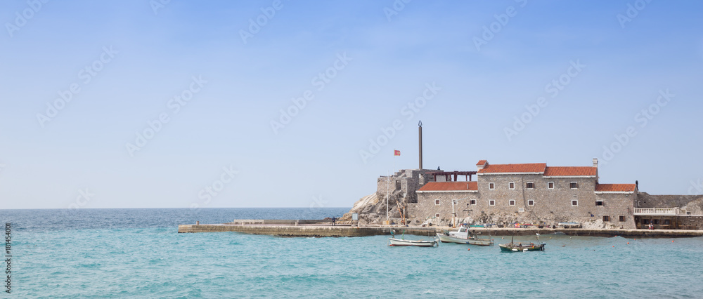 Panorama of stone pier, boats,  house with  red roof and  sea