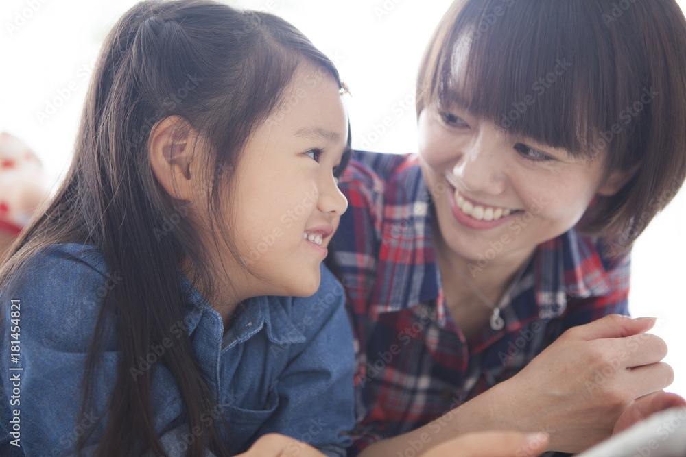 Mother and daughter are using a digital tablet at the table together. Mother and daughter are using a digital tablet at the table together.