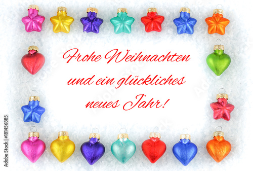 Colorful Christmas tree decorations on snow with German Christmas greetings, white background © Angela Rohde