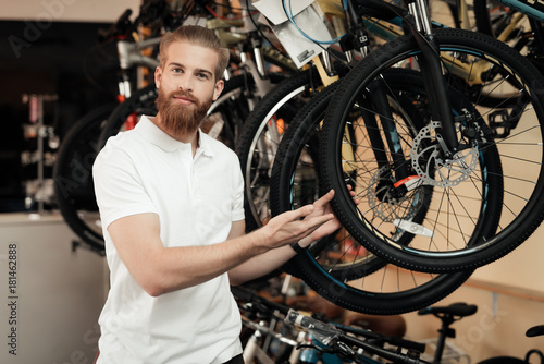 A salesman in a bicycle shop poses near a bicycle.