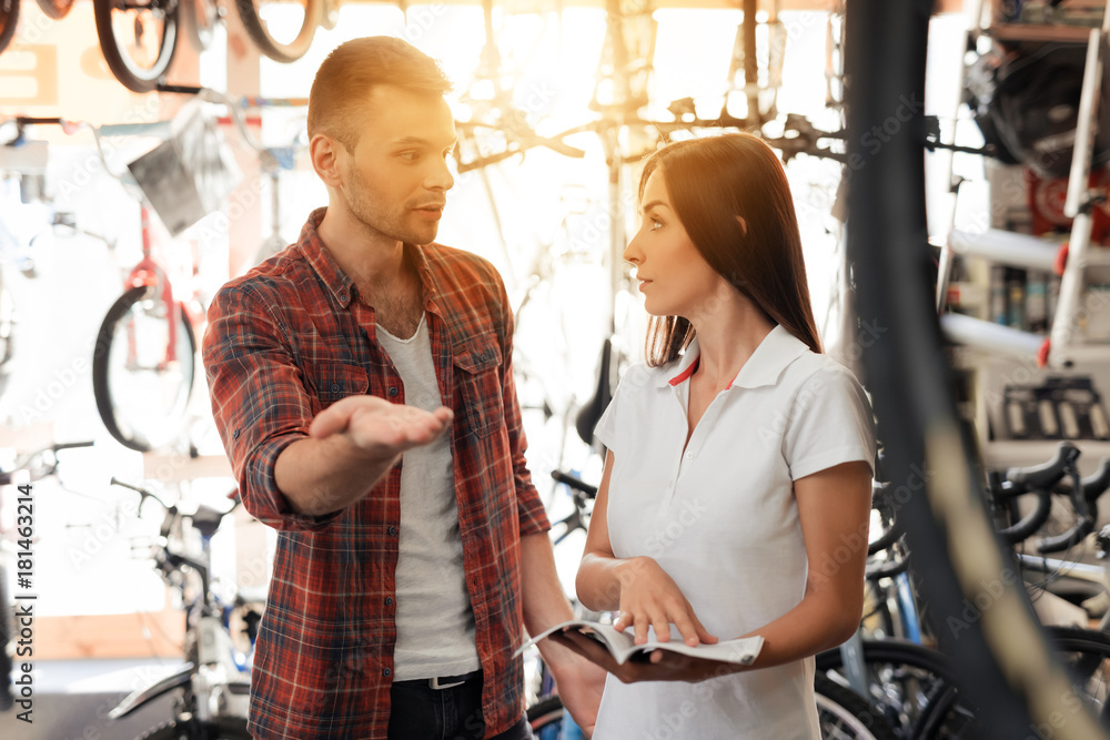 A girl consultant shows the buyer in a bicycle store.